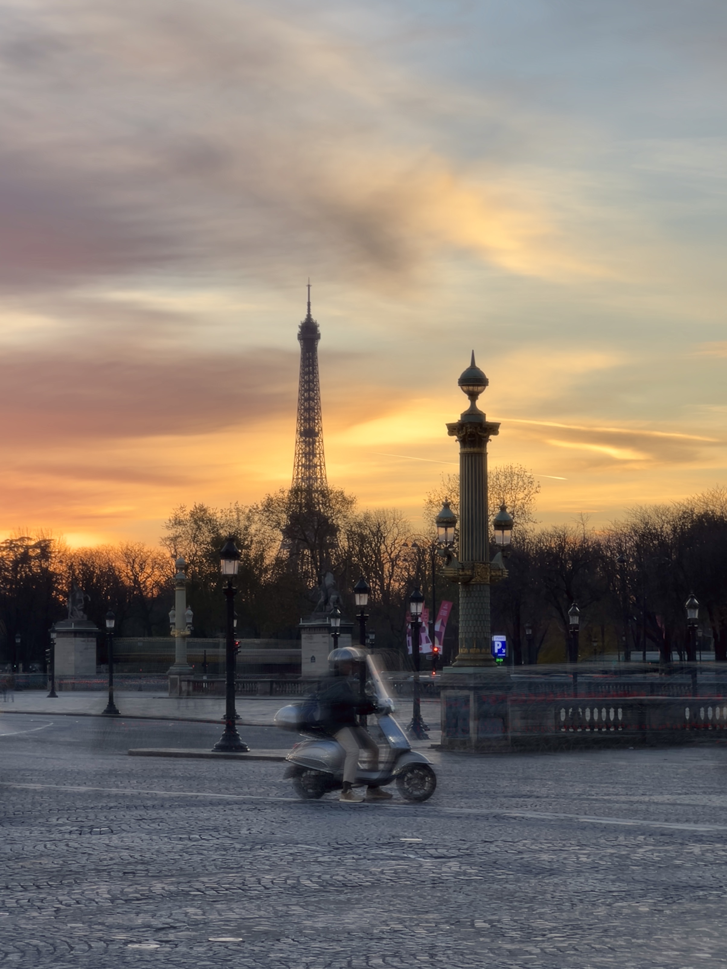 A photo of the Eiffel Tower from Concorde with a blurry motorcycle in the mid ground