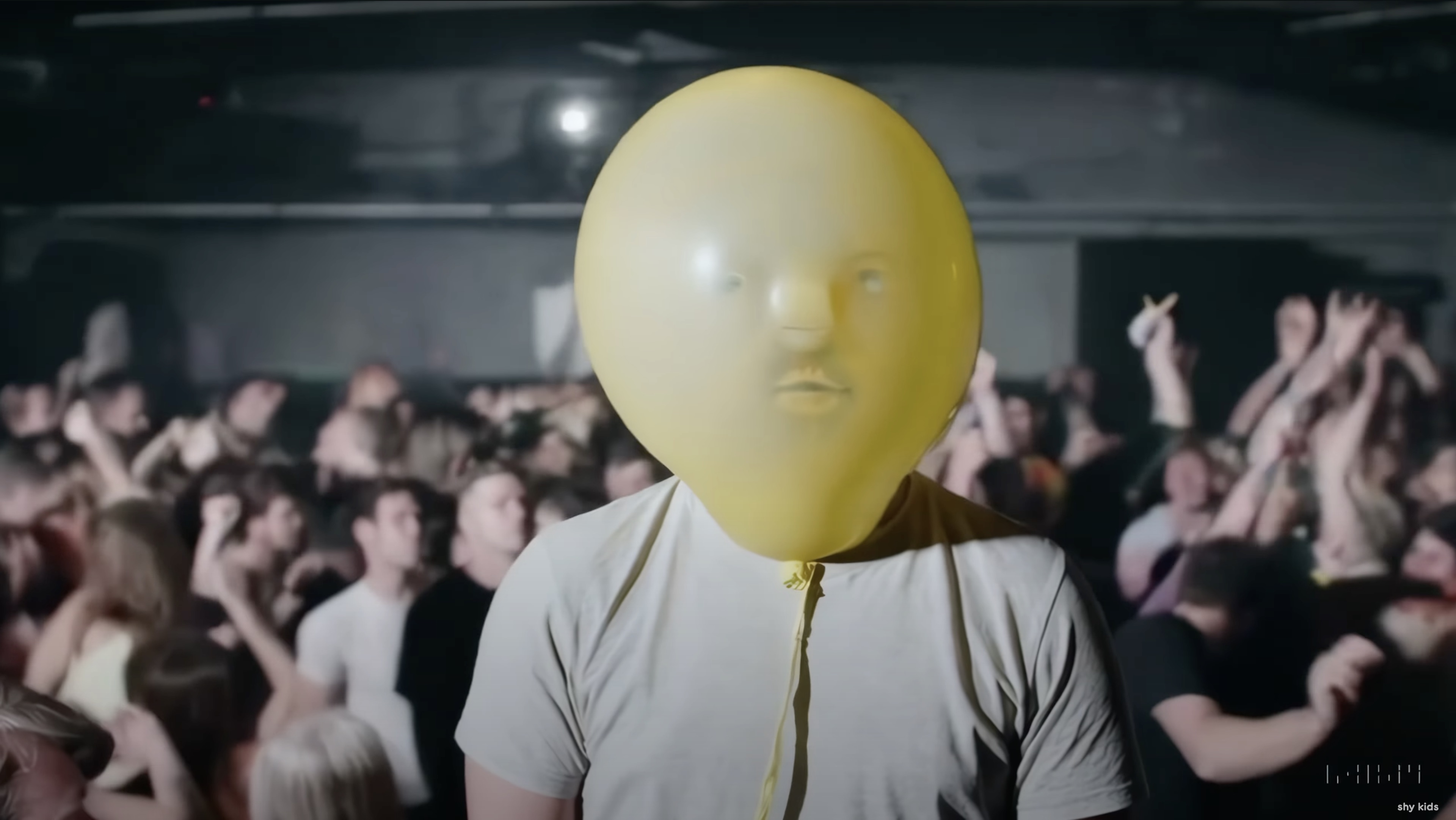 A still frame from the BTS 'air head' video. A yellow balloon head with a weird face.