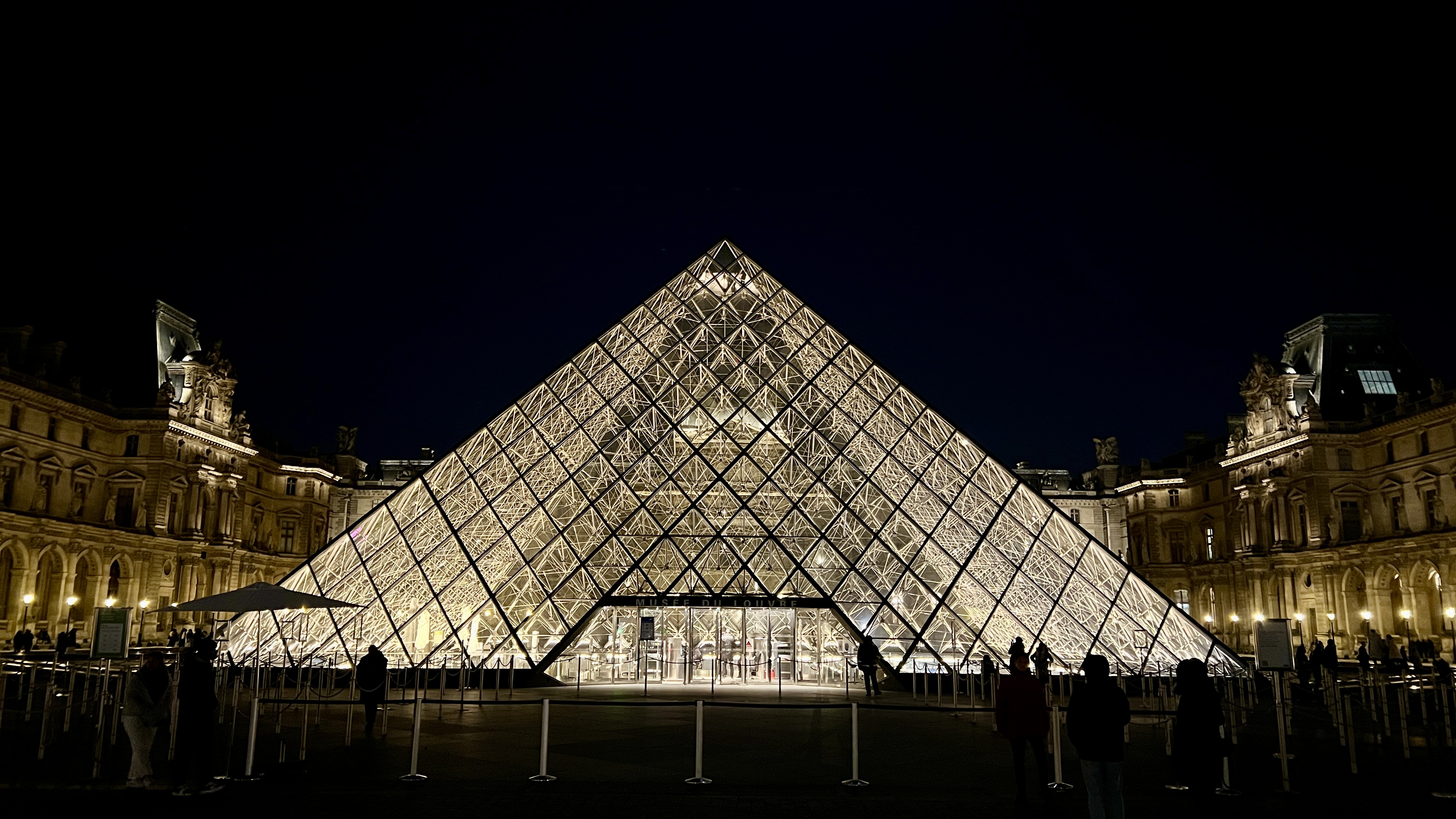 The Louvre at night with some putzes in the foreground.